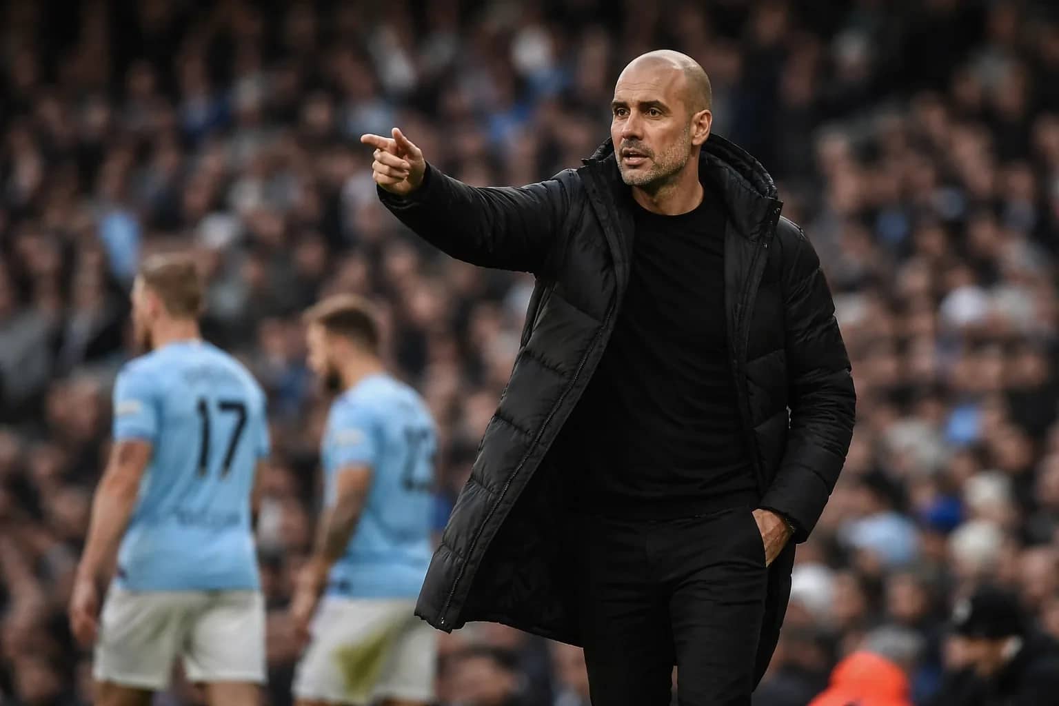 Pep Guardiola gesturing on the touchline during a Manchester City match.