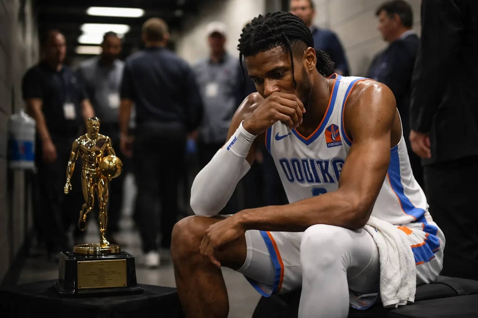 Shai Gilgeous-Alexander holding the NBA MVP trophy at center court during a pre-game ceremony.