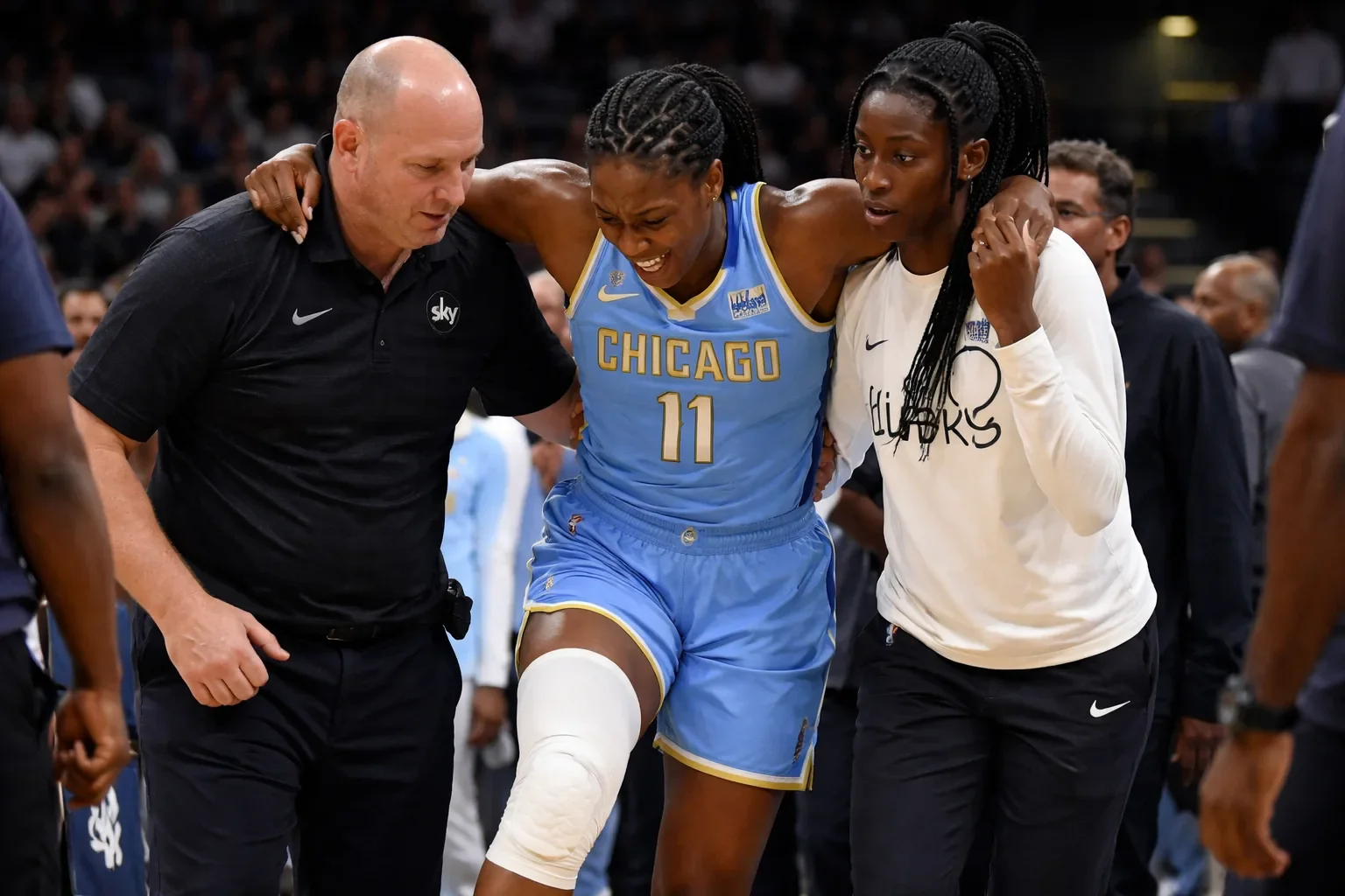Rickea Jackson of the Chicago Sky being helped off the court after sustaining a knee injury during a WNBA game.